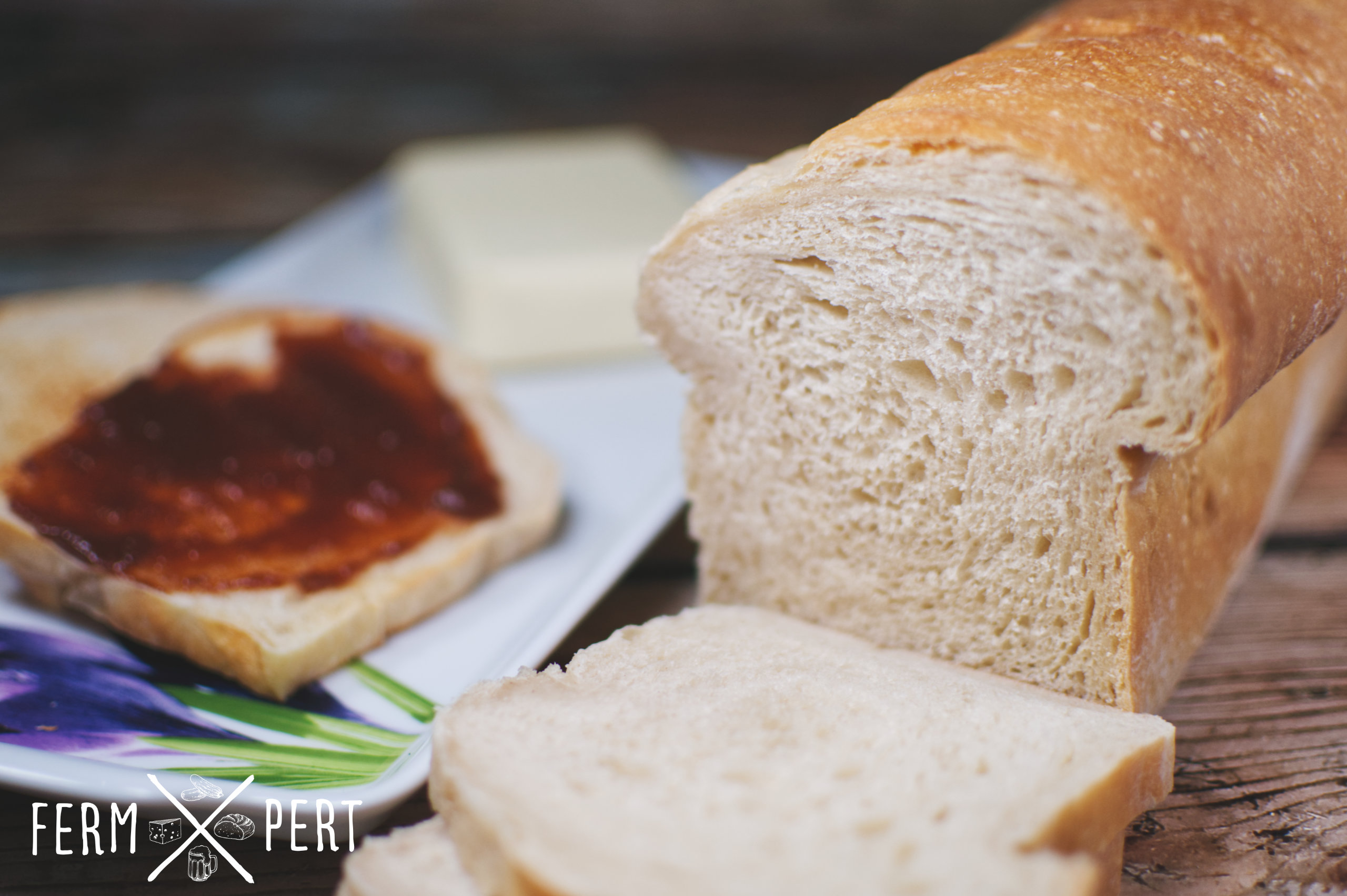 Photo of a loaf of sandwich bread with a toast with jam on the left.