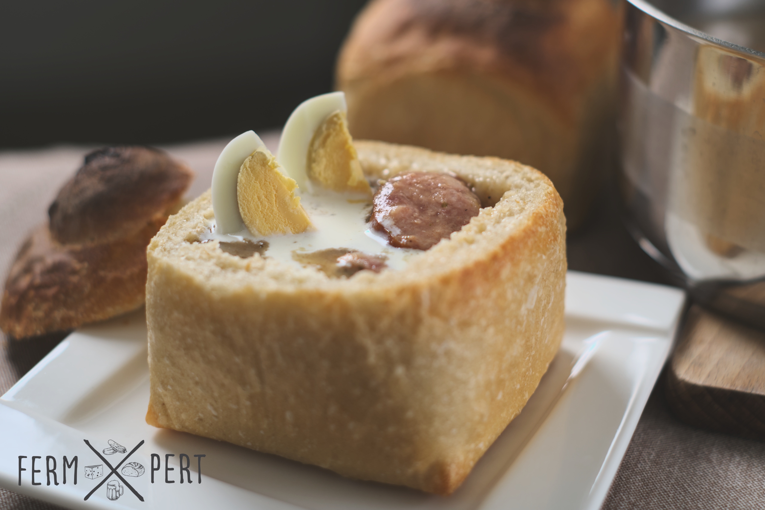photo of soup in a hollowed out loaf of bread with sausage and egg sticking out